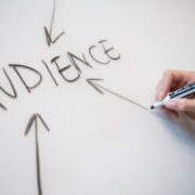 White board with the word "AUDIENCE" written on it, and a white person's hand holding a marker that has just drawn 3 arrows toward the word to give it emphasis